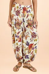 Pantalón tipo aladín con cintura elástica y puños ajustados en los tobillos. Presenta un estampado botánico multicolor sobre fondo blanco.