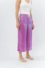 Pantalón de lino con acabado metalizado tornasolado, que refleja tonos entre rosa y lila según la luz. De corte recto y largo ¾, tiene cintura con elástico en la espalda que aporta comodidad y un calce relajado.