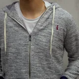 Campera gris jaspeado con capucha y cierre frontal, puños y cintura acanalados en azul marino, y logo bordado en el pecho.