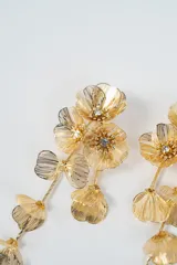 Aros colgantes largos de diseño floral, compuestos por múltiples pétalos metálicos texturizados en color plateado, con pequeños cristales incrustados en el centro de las flores superiores.