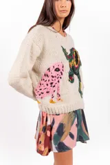 Sweater de lana merino color beige, tejido a mano con diseño holgado, cuello redondo y bordados artesanales de ranas y detalles coloridos.