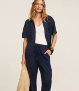 Pantalón largo verde militar de corte fluido, con cintura elástica, cordón de ajuste y bolsillos cargo en los laterales.