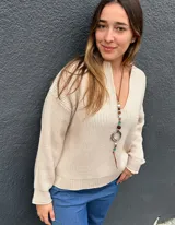 Buzo de punto color crudo, con escote en V pronunciado, mangas largas y puños acanalados.