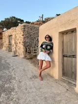 Falda corta blanca de corte globo, confeccionada con elástico y cierre en la cintura.