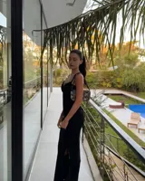 Vestido largo negro de tirantes finos, con escote festoneado y corte al cuerpo con abertura lateral en la falda.