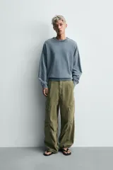 Sudadera de corte relaxed fit confeccionada en tejido de algodón con interior de rizo. Presenta cuello redondo, manga larga y acabados en rib, con un acabado de efecto lavado que le otorga una apariencia única.