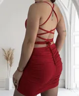 Vestido corto rojo ajustado al cuerpo, con escote en V y breteles finos. Presenta frunces verticales en el centro.