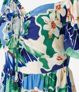 Vestido largo de viscosa con estampado tropical de flores blancas y hojas verdes y azules. Presenta escote cuadrado con lazo ajustable en el centro del busto y mangas cortas abullonadas. La falda es escalonada con volados.