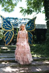 Vestido largo de gasa color rosa con estampado floral, cuello halter, corte en la cintura con cordón ajustable y falda con volantes.