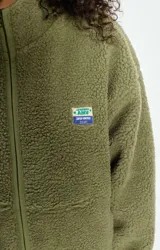 Campera de corderito con efecto shearling, color verde oliva, de corte holgado, cuello alto y cierre frontal completo. Presenta un pequeño parche con logo en el pecho.