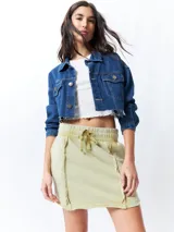 Minifalda color beige con elástico en la cintura, cordones ajustables y costuras marcadas en los laterales.