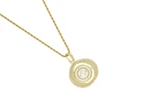 Collar de cadena tipo soga en tono dorado con dije circular compuesto por anillos concéntricos incrustados con circonias y una perla central.