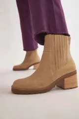 Botas de cuero color beige con elástico en los laterales, taco de madera y suela de goma.