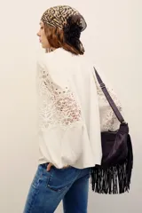 Camisa blanca de manga larga con detalles de encaje guipure en el pecho y las mangas, cuello en V y corte holgado.