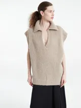 Poncho de punto color azul, con cuello polo y escote en V profundo, sin mangas y diseño holgado.