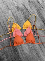 Corpiño de bikini tipo triángulo con copas removibles. Se ata en la espalda y tiene tiras ajustables que también permiten atarlo al cuello.