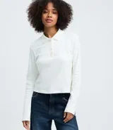 Blusa tipo polo de manga larga confeccionada en algodón, con cuello clásico y cierre frontal de botones. Presenta un diseño de corte regular y acabado suave.