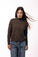 Sweater de tejido de punto con textura de pequeños relieves circulares, cuello redondo y mangas largas. Presenta un calce relajado con puños y ruedo acanalados.