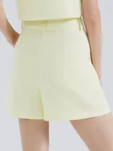 Short de vestir color amarillo pastel, de tiro alto con pinzas y bolsillos laterales.