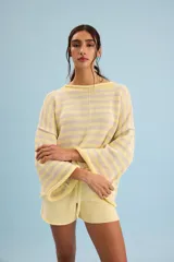 Buzo de algodón tejido con patrón de rayas horizontales en tonos amarillo, crudo, celeste y rosado, con diseño holgado y mangas anchas.