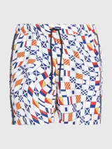 Short de baño blanco con estampado de banderas náuticas en azul, rojo y amarillo. Tiene cintura elástica con cordón ajustable, bolsillos laterales y logo de Tommy Jeans en la pierna.
