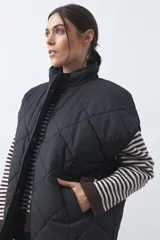 Chaleco acolchado de nylon con diseño capitoneado, cuello alto y cierre frontal con botones a presión. Presenta un calce amplio y versátil.