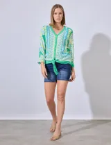 Blusa estampada con escote en V, abertura central con botones y terminación anudada. Largo de manga regulable con presilla y botón.