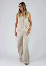 Chaleco sastrero sin mangas, de color beige con diseño de rayas verticales, cuello en V y cierre frontal con botones.
