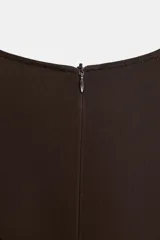 Blusa de viscosa color marrón oscuro, con cuello redondo y manga larga ancha estilo evasé. Presenta un corte recto y cierre de cremallera oculta en la espalda.