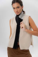 Chaleco de punto confeccionado en lambswool, de corte recto y sin mangas. Presenta cierre frontal completo y un diseño de cuello alto con vista central en combinación de color negro y gris.
