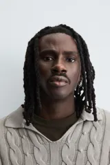 Polo de algodón tejido con estructura de trenzas, cuello solapa con abertura frontal en V y manga larga. Presenta acabados en rib con efecto roto en puños, cuello y ruedo.