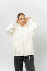 Campera con capucha y cierre frontal, de corte oversize, confeccionada en tejido suave con interior forrado en piel sintética. Presenta bolsillos tipo canguro, capucha amplia con cordones largos y puños elásticos.