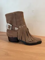 Bota de cuero vacuno color marrón, con diseño versátil que permite cuatro formas de uso. Presenta flecos decorativos, una correa con hebilla metálica estilo western y detalles de tachas. Cuenta con taco cuadrado de madera y punta fina.