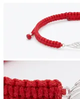Pulsera de hilo rojo tejida en macramé con dije central en forma de ala de plata 925 y terminaciones con esferas de plata. Diseño regulable.