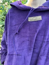 Vestido corto de terciopelo color violeta, con capucha, cordón ajustable, mangas largas abullonadas y bolsillo tipo canguro.