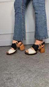 Sandalias con taco ancho y plataforma, confeccionadas en combinación de napa blanca, cuero texturizado croco negro y napa camel. Cuentan con tira trasera con hebilla metálica regulable.