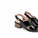Sandalias de cuero charol negro con tiras cruzadas en el empeine, pulsera ajustable al tobillo con hebilla metálica dorada, taco ancho efecto madera y suela tractorada.