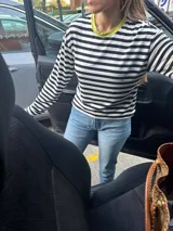 Remera corta de algodón a rayas horizontales blancas y negras, con cuello redondo en color fucsia y parche bordado en la manga izquierda.