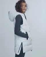 Chaleco largo negro estilo puffer con capucha y cierre frontal.