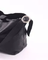 Cartera tipo hobo de cuero natural, color negro, con correa regulable y cierre superior. El interior cuenta con tres compartimentos divididos por un bolsillo central con cierre.