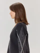 Buzo de lana con escote en V, diseño de rombos y detalles en hilo metalizado. Presenta mangas largas y corte holgado.