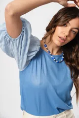 Blusa azul de cuello redondo y manga corta abullonada con puño elástico.