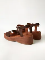 Sandalias de plataforma color chocolate con tira frontal ancha de gamuza y tira al tobillo con hebilla metálica ajustable.