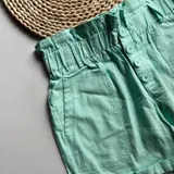 Short color amarillo pastel con cintura elastizada y detalle de botones frontales.