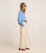 Pantalón wide leg de cintura alta en sarga de sastrería color marfil, con bolsillos cargo en los laterales y cierre frontal con botón y cremallera.