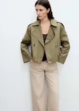 Chaqueta corta de estilo trench con cuello de solapa y cierre frontal de doble botonadura. Presenta diseño recto, manga larga y bolsillos laterales, confeccionada en tejido de mezcla de algodón con forro interior.