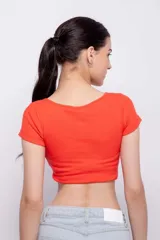 Top blanco de corte crop, escote redondo pronunciado y mangas cortas ajustadas.
