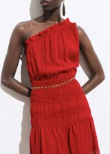 Vestido corto rojo de un solo hombro, con volados en el escote, cintura elastizada con cinturón de cadena dorada y falda con frunces.