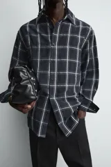 Camisa de corte relajado confeccionada en tejido fluido de cupro y viscosa, con estampado de cuadros, cuello solapa, manga larga con puño abotonado y cierre frontal de botones.