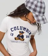Remera de algodón con elastano, color blanco, de corte ajustado al cuerpo y manga corta. Cuenta con cuello redondo y estampa frontal estilo college con un oso sentado, la inscripción "Columbia", el número 1989 y la frase "Calm and Cute Bears".